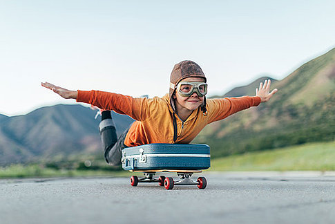 Kind mit Fliegermütze auf Skateboard